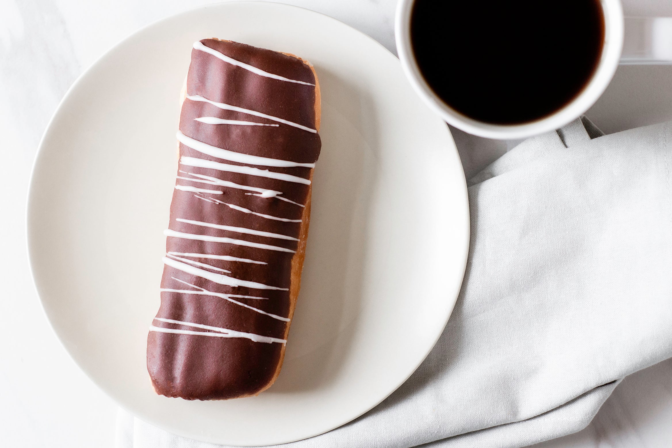 Chocolate Iced Custard Filled Long John with White Drizzle